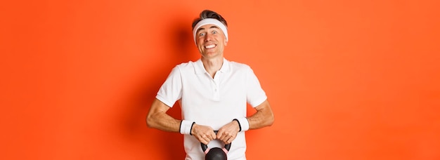 Bezpłatne zdjęcie koncepcja siłowni i styl życia portret śmiesznego sportowca w średnim wieku próbującego podnieść kettlebel