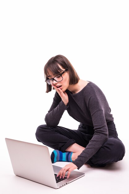 Koncepcja szkoły, edukacji, internetu i technologii - młoda dziewczyna nastolatka siedzi na podłodze z laptopa
