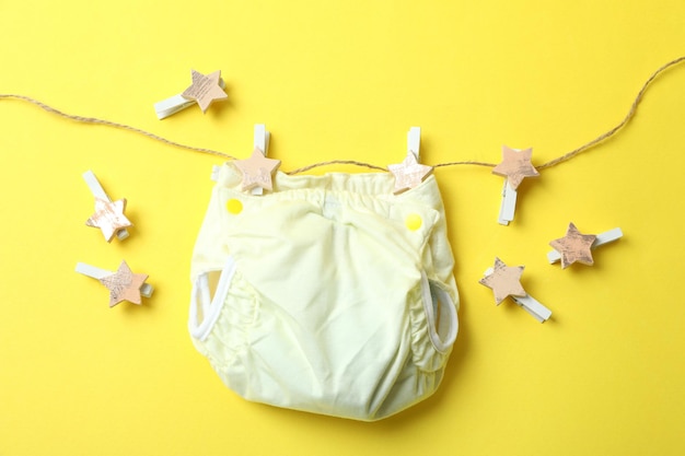 Koncepcja ubranek dla dzieci z pieluchami wielokrotnego użytku na żółtym tle
