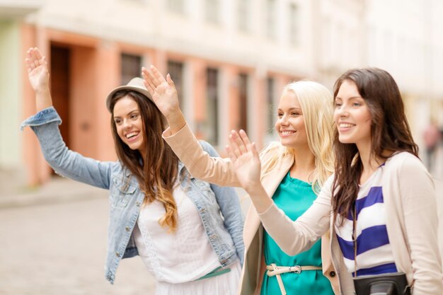 Koncepcja wakacji i turystyki - trzy piękne dziewczyny machające rękami w mieście