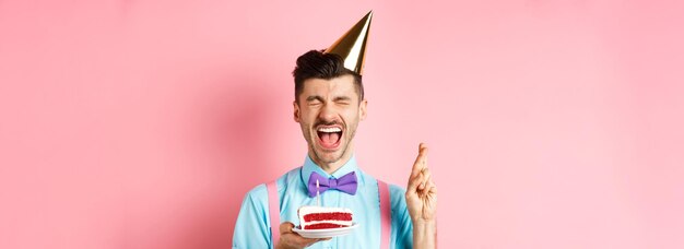 Bezpłatne zdjęcie koncepcja wakacji i uroczystości podekscytowany facet świętujący urodziny i życząc sobie krzyżyków