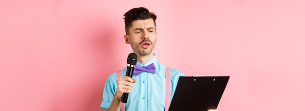 Bezpłatne zdjęcie koncepcja wakacji poważnie wyglądający mężczyzna czytający skrypt ze schowka trzymający mikrofon zabawiać ludzi