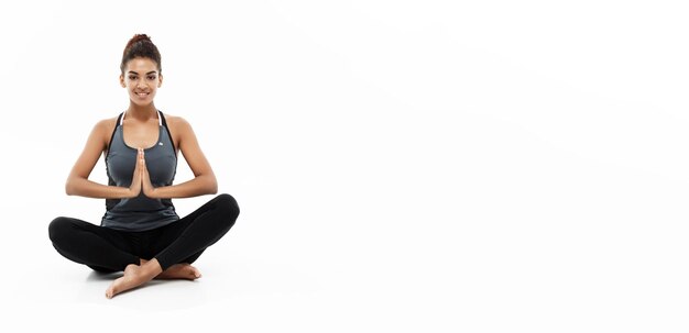 Koncepcja zdrowego i fitness Piękna amerykańska dama Afryki w odzieży fitness robi joga i medytacja izolowany na białym tle