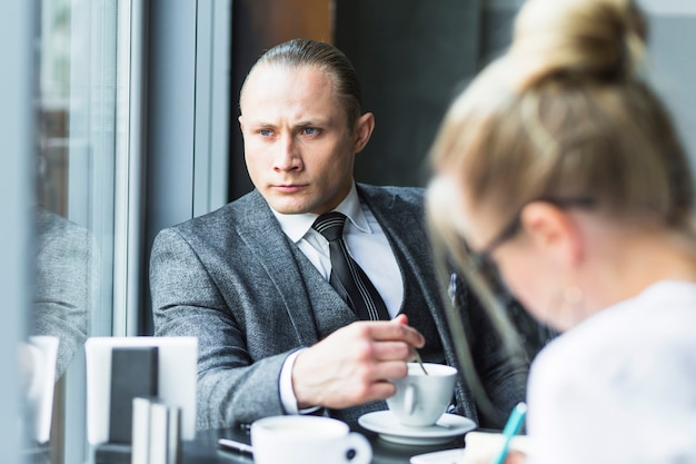 Kontemplowany biznesmen z filiżanką herbaty, siedząc w restauracji