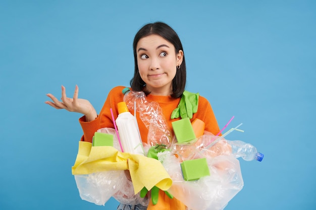 Koreańska Dziewczyna Z Plastikowymi śmieciami Wzrusza Ramionami, Nie Wie, Jak Sortować Odpady Na Recykling Za R