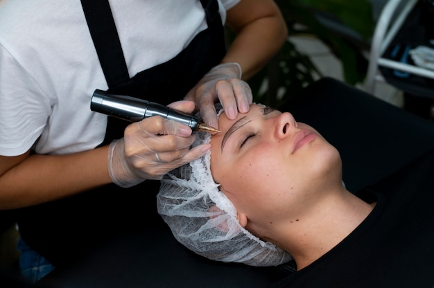 Bezpłatne zdjęcie kosmetyczka wykonująca zabieg microblading na kobiecie w salonie kosmetycznym