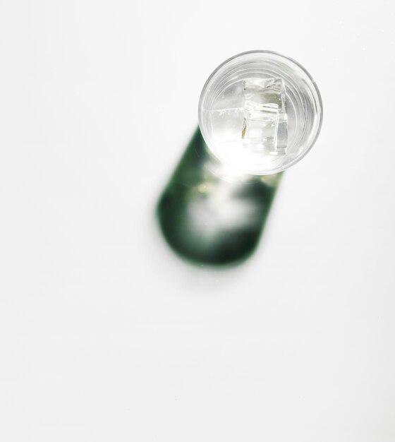 Bezpłatne zdjęcie kostki lodu w szklance wody z błyszczącym cieniem na białym tle