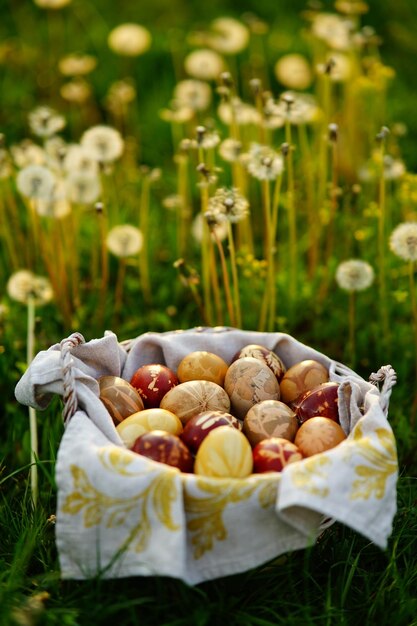 Koszyk wypełniony zdobionymi jajkami wielkanocnymi na polu mniszka lekarskiego