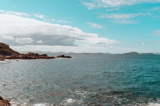 Bezpłatne zdjęcie krajobraz morza otoczony wyspą pokrytą zielenią pod zachmurzonym niebem
