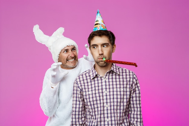 Bezpłatne zdjęcie królik przerażający pijany mężczyzna nad fioletową ścianą. przyjęcie urodzinowe.
