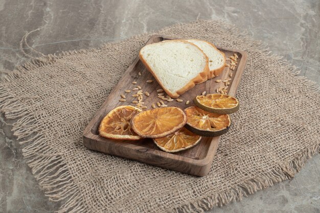 Kromki chleba i suszona pomarańcza na drewnianym talerzu. Wysokiej jakości zdjęcie