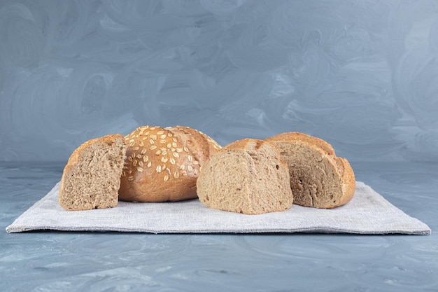 Bezpłatne zdjęcie kromki chleba na złożonym obrusie na marmurowym stole.