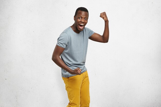 Kryty strzał przystojny podekscytowany szczęśliwy młody student afroamerykanów wykrzykuje z podniecenia