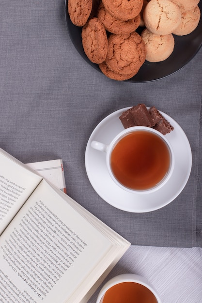 Książka, filiżanka herbaty i czekolady na stole