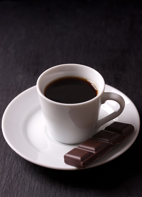 Kubek czarnej kawy z kawałkiem czekolady
