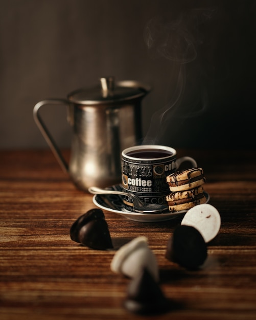 Kubek gorącej kawy z ciasteczkami na stole pod lampkami - idealny do konceptów napojów