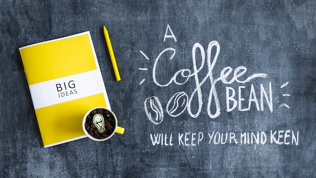 Bezpłatne zdjęcie kubek z kawowymi fasolami z żarówką nad dużymi pomysłami rezerwuje tekst na blackboard i książka