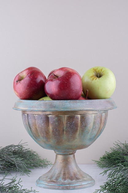 Bezpłatne zdjęcie kupie jabłka w metalowym wazonie na białej powierzchni