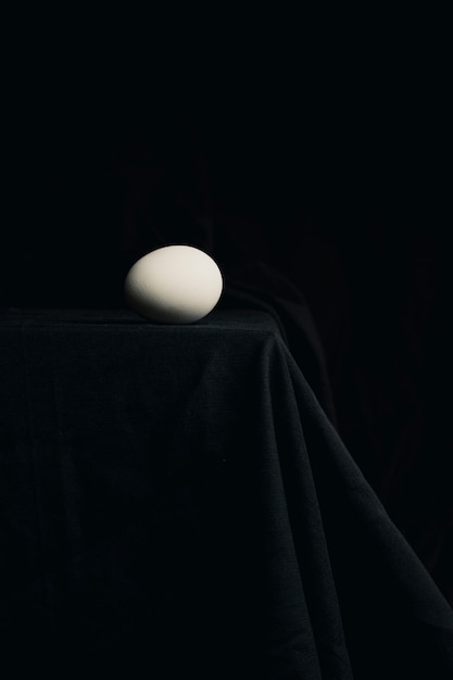 Kurczak jajko na krawędzi stół między ciemnością