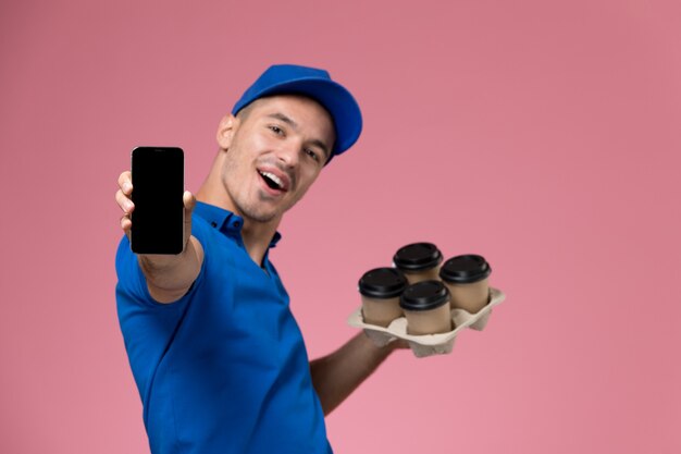 Kurier W Niebieskim Mundurze Trzymający Dostawę Kawy I Telefon Na Różowym, Jednolitym Dostawie Usług