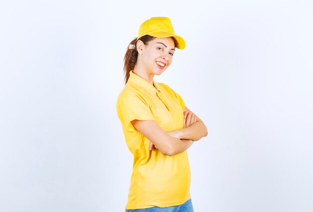 Kurierka w żółtym mundurze krzyżująca ramiona i dająca profesjonalne pozy.