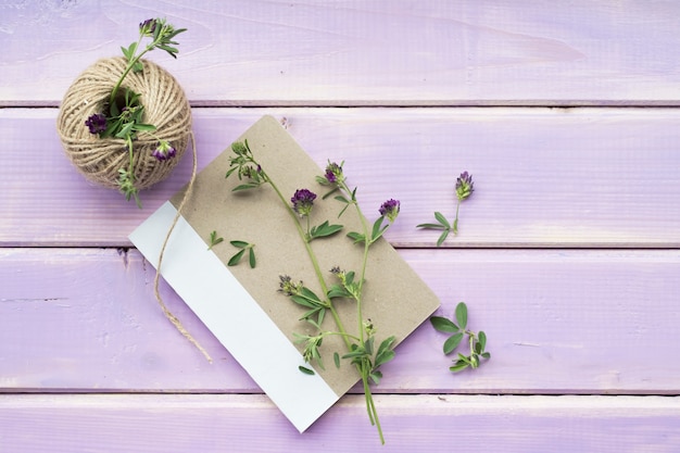 Bezpłatne zdjęcie kwiat gałązki na zamkniętym notatniku z cewą sznurek na purpurowym drewnianym tle