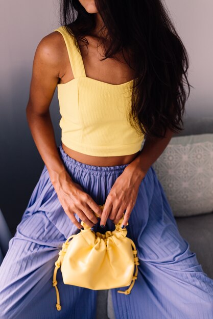 ładna blogerka modowa ubrana w żółty top i fioletowe spodnie
