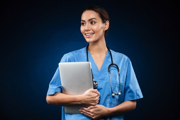 Ładna damy lekarka patrzeje na boku z laptopem