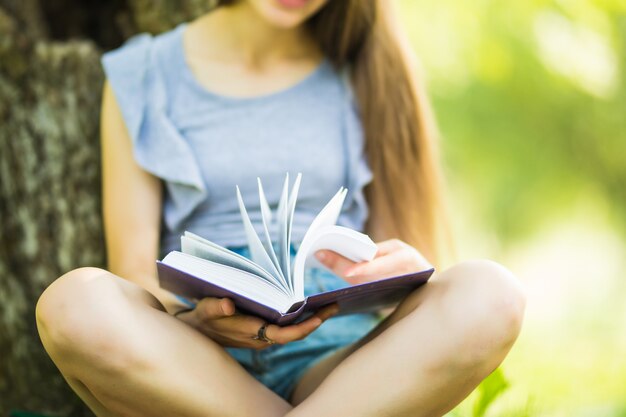 Ładna dziewczyna, czytanie książki w parku. Student przygotowuje się do egzaminu. Literacki wypoczynek na świeżym powietrzu.