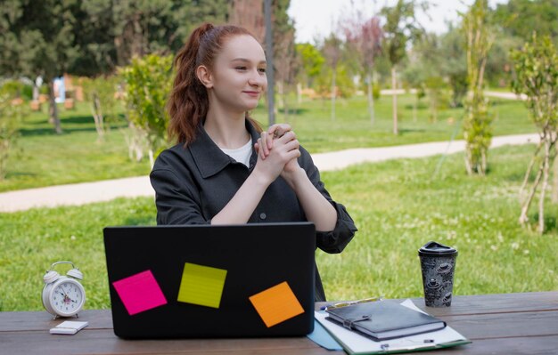 Ładna dziewczyna pracuje przy laptopie w aprku ręce w zamku