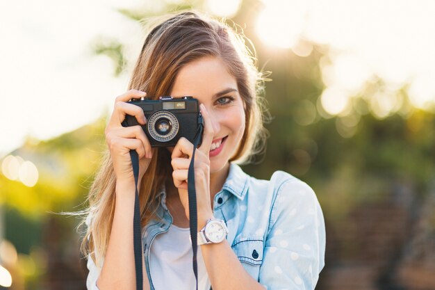 Ładna dziewczyna robi zdjęcia aparatem vintage w słoneczny dzień