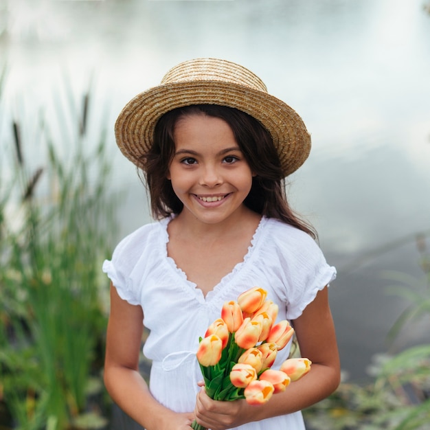 Ładna dziewczyna trzyma kwiaty nad jeziorem