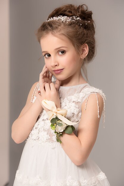 Ładna dziewczynka z kwiatami ubrana w suknie ślubne