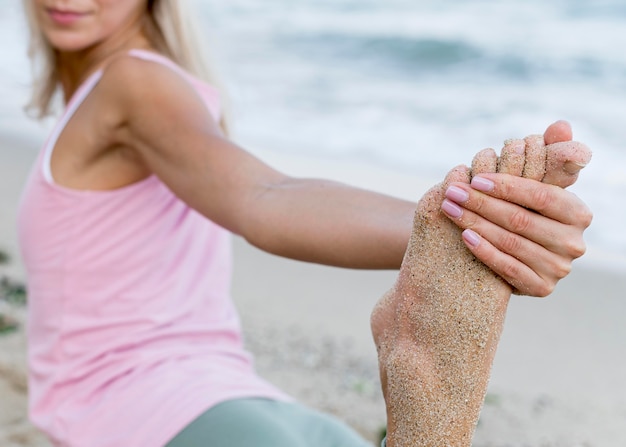 Bezpłatne zdjęcie Ładna kobieta praktykuje jogę na plaży