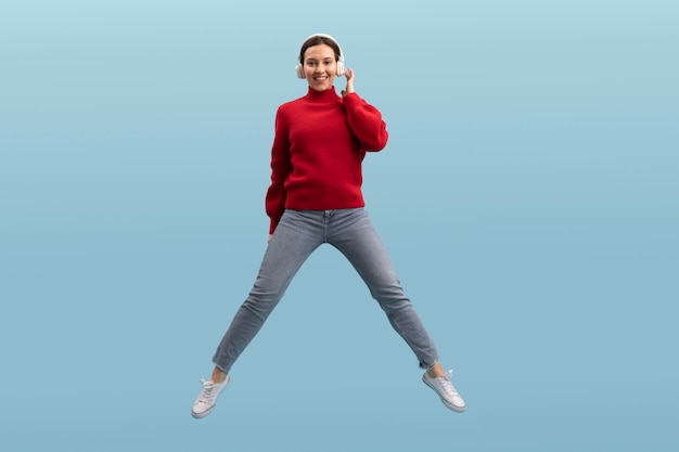 Bezpłatne zdjęcie Ładna kobieta skoki na białym tle na niebiesko