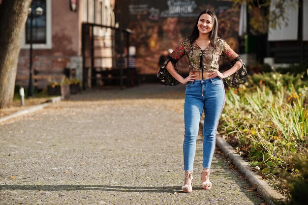 Ładna latynoska modelka z Ekwadoru nosi dżinsy pozowane na ulicy