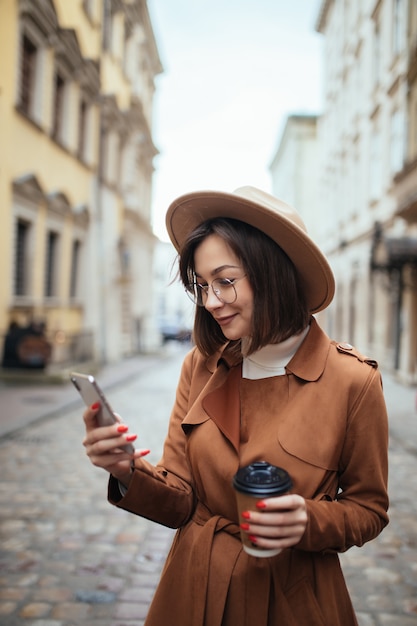 Ładna młoda dama opowiada na telefonie komórkowym chodzi outdoors w zimnym jesień dniu