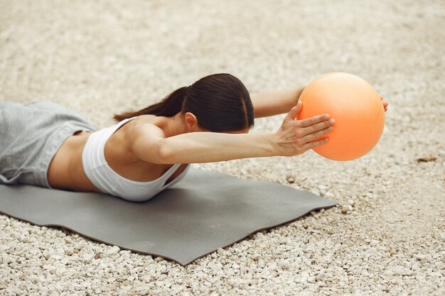 Ładna pani trenująca na letniej plaży. Brunetka robi joga. Dziewczyna w stroju sportowym.