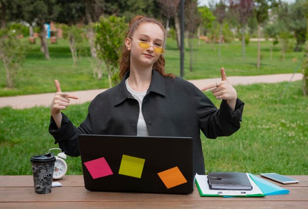 Ładna studentka-programistka-freelancerka pracująca na laptopie patrząca na kamerę