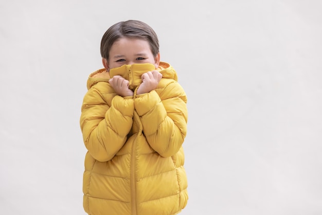 Ładny chłopak ubrany w żółte ubrania zimowe przygotowuje się do nadchodzącego sezonu zimowego.