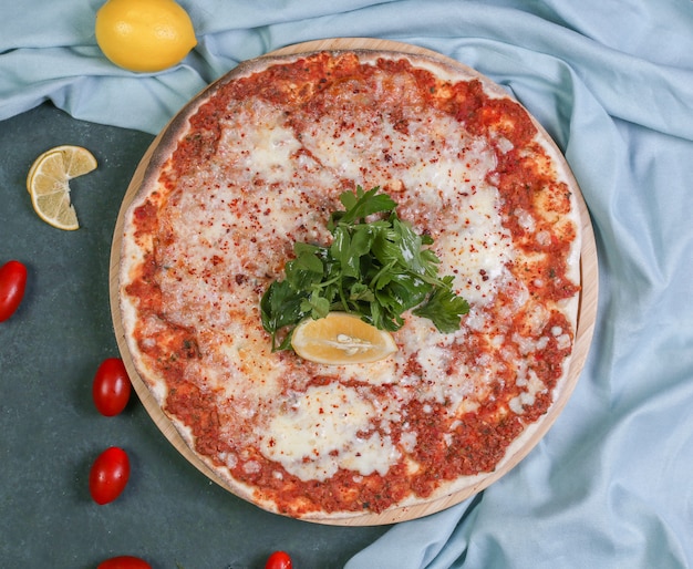 Bezpłatne zdjęcie lahmacun z tureckiego jedzenia ulicznego z cytryną, świeżą pietruszką i topionym serem na wierzchu.