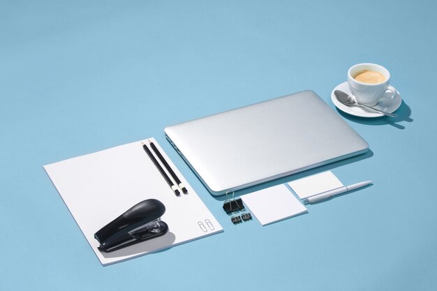 Laptop, długopisy, telefon, notatka z pustym ekranem na stole