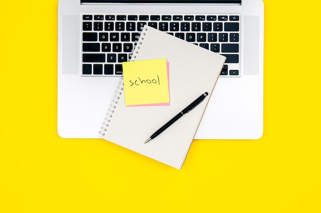 Bezpłatne zdjęcie laptop i notatnik na żółtym tle widok z góry