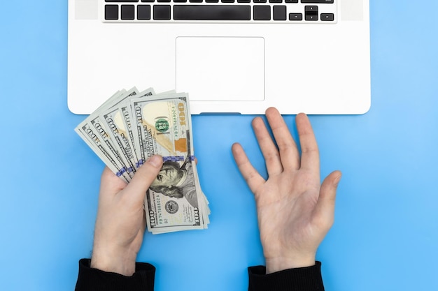 Laptop i pieniądze w męskich rękach widok z góry
