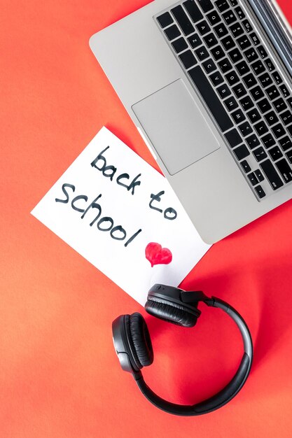 Laptop i słuchawki na czerwonym tle koncepcja powrotu do szkoły
