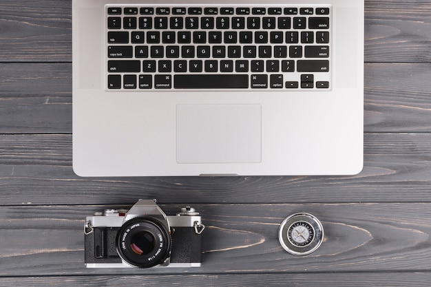 Bezpłatne zdjęcie laptop z kamerą i kompasem na drewnianym stole