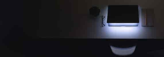 Bezpłatne zdjęcie laptop z świecącym ekranem na stole w ciemnej przestrzeni kopiowania widoku górnego