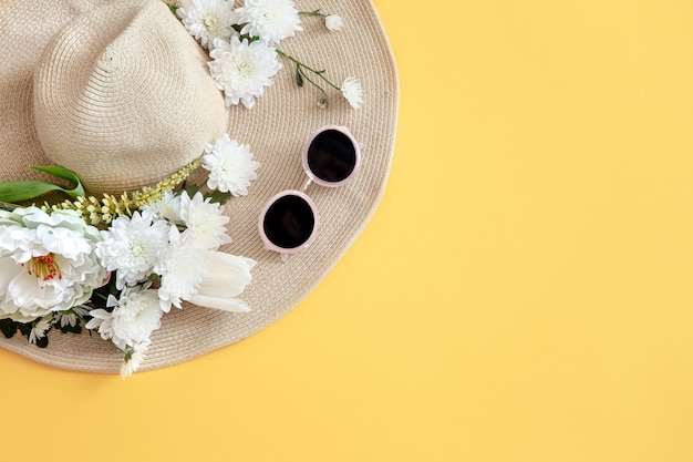 Bezpłatne zdjęcie lato z białymi kwiatami i wiklinową czapką z okularami przeciwsłonecznymi