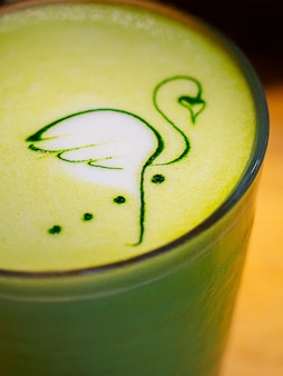 Latte art rysunek flamingów na piance z gorącą herbatą matcha na mleku kokosowym
