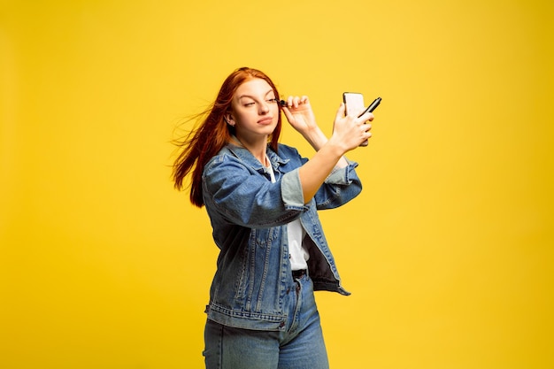 Łatwiej jest być naśladowcą. Nie potrzebujesz selfie do makijażu. Portret kobiety kaukaski na żółtym tle. Piękne kobiece włosy model. Pojęcie ludzkich emocji, wyraz twarzy, sprzedaż, reklama.